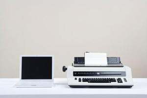 Laptop next to typewriter on table laptop next to typewriter on table